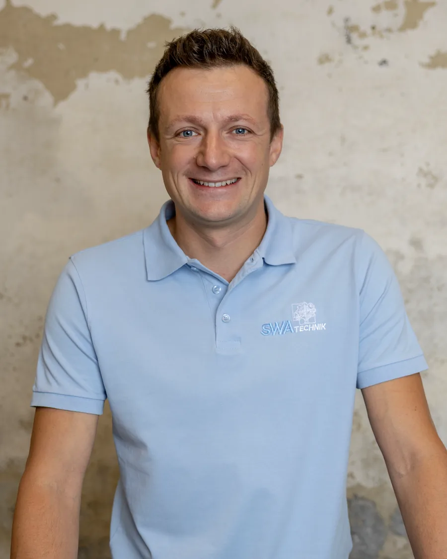 Andreas Schmid-Waldenberger im Poloshirt von SWA Technik vor einer Betonwand